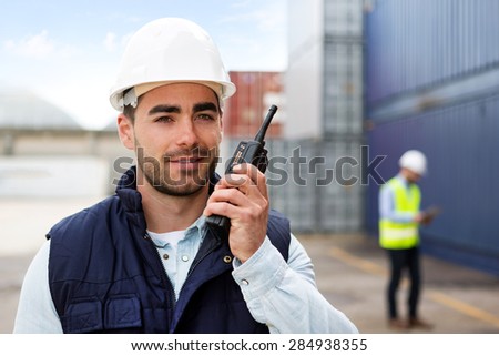 View of a Young Attractive docker using talkie walkie at work