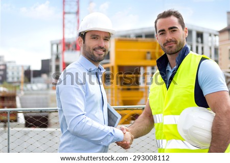 View of an architect and worker handshaking on construction site