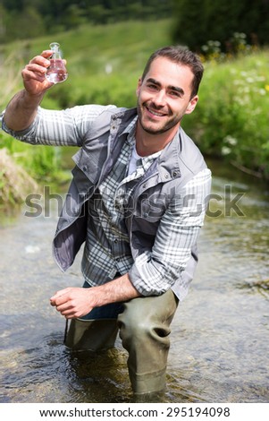 View of a Biologist take a sample in a river in order to do some test