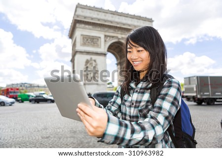 View of a Young attractive asian tourist using tablet in Paris