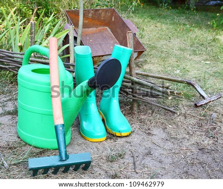 Green garden watering-can rubber knee-boots and rakes. Garden inventory