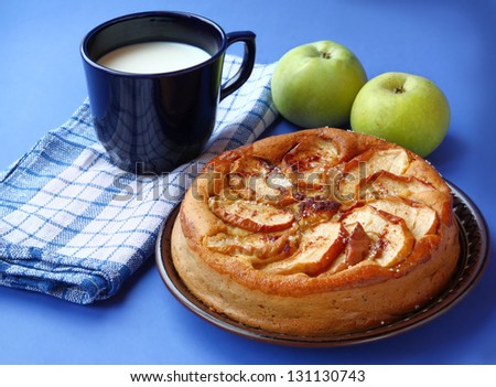 Handmade apples cake and dark blue cup with milk on a dark blue background