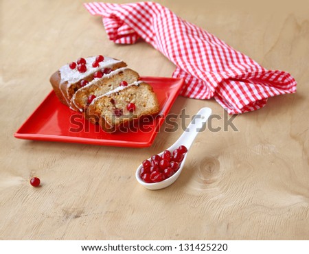 Cranberry cake on a red dish  and porcelain spoon with the berries of cranberry on a wooden table