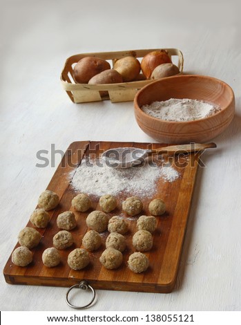 Dumplings on a board and bowl with a flour and potato on a cook-table