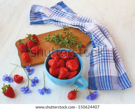 Summer still-life with blue cornflowers and fresh strawberries on a kitchen table