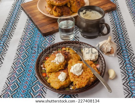 Traditional Ukrainian homemade potato pancakes potato, carrot and pumpkin with sour cream and glass of vodka