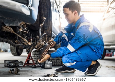 Mechanic Asian man fixing repairing car rotor spindle hub wheel automobile vehicle parts examining using tools equipment working hard in workshop garage support and service in overall work uniform 商業照片 © 