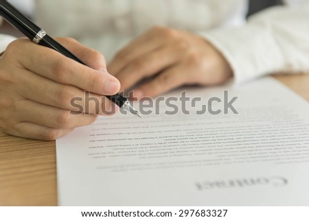 closeup pen in hand\'s  businessman preparing to sign an important document.