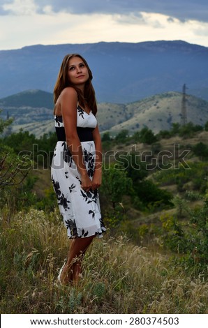 Beautiful, charming, charming girl model in white dress posing on a background of mountains and sky in the resort of the Black Sea. Republic of Crimea, Ukraine.