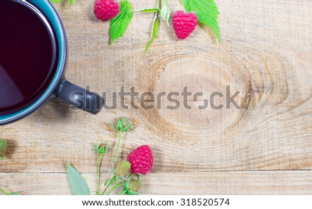 Tea raspberry on a wooden background with fresh raspberries.