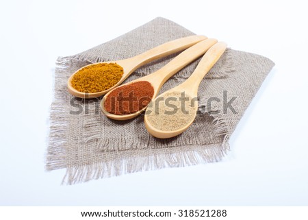 Spice powder isolated on white background. Paprika, curry and ginger on a wooden spoon.