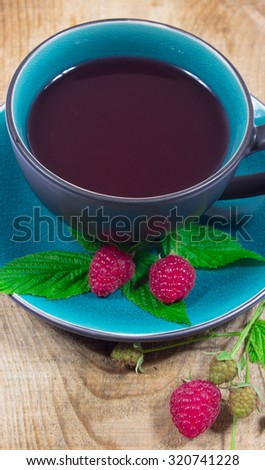 Tea raspberry on a wooden background with fresh raspberries.