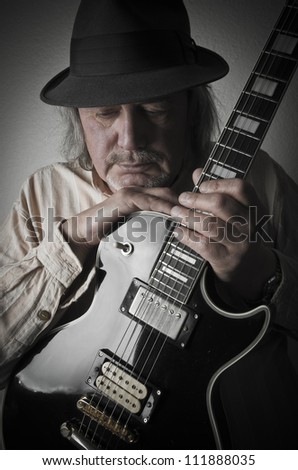Blues guitarist wearing hat with black solid body guitar