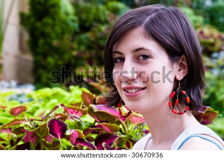 The Red Earring Attractive young woman wearing red earrings near coleus plants