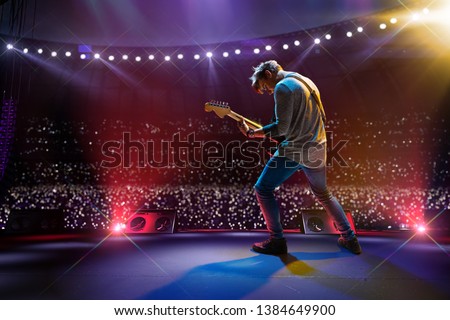 Rock star celebrity on the main stage big music festival. Aroun full stadium of spectators. fans are holding flashlights