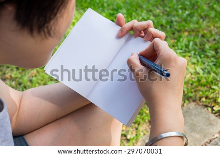 One taking note with book on left hand and pen on right hand