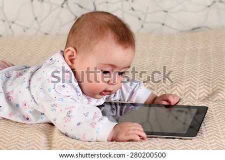 A six-month baby with a tablet computer, looking at screen, at home