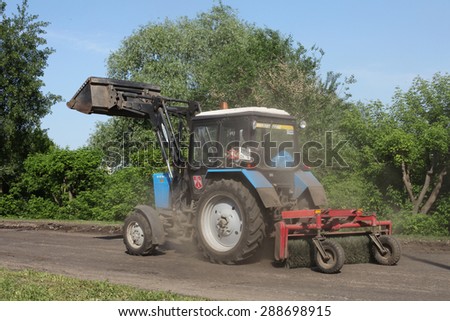 NABEREZHNYE CHELNY - JUNE 1, 2015: Road repairing on Gabdully Tukaya embankment. Tractor with brush sweeping the road.