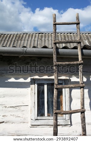Old wooden ladder on wooden wall over window under slate roof