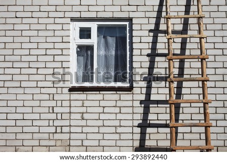 Wooden ladder on brick wall near window