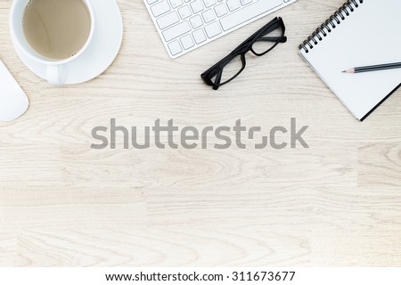 Office table with notepad, mouse,keyboard , coffee cup,black glasses. View from above with bottom copy space / clean desk from top view