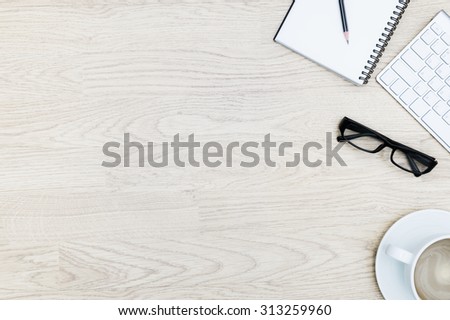 Office table with notepad, mouse,keyboard , coffee cup,black glasses. View from above with bottom copy space / clean desk from top view with left copy space