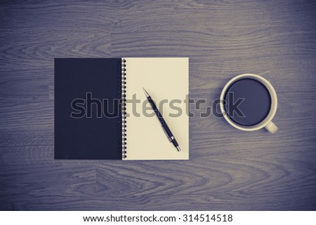 coffee in white cup,white notepad cover,black pencil with wood background black and white vintage picture color style.