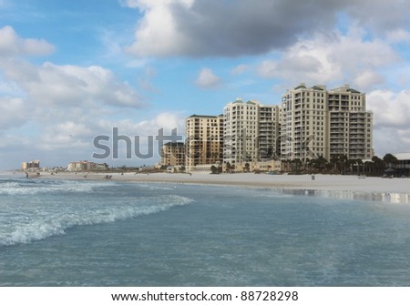 Beautiful beach scene with high rise beach front hotels in the distance.