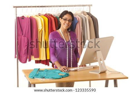Young Hispanic fashion designer standing at work table with computer