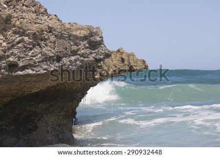 Blue sky, blue sea and rocks. Waves, surf and white sea foam.