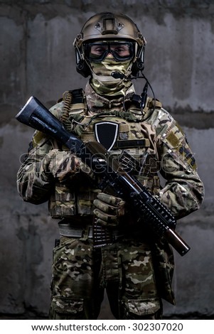 Armed soldier in camouflage, mask,helmet with rifle in hands looking at the camera