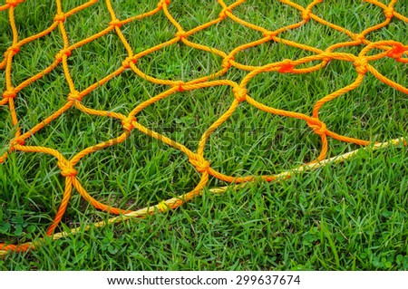 Orange football goal net on green grass