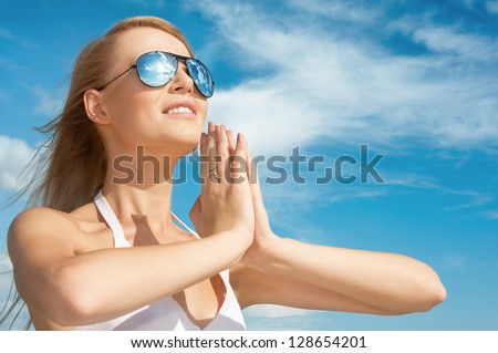 Dreamy young woman in mirrored sunglasses on sky background