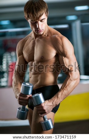 Portrait of sporty muscular guy doing workout in fitness club