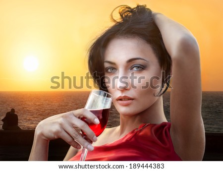 Portrait of glamorous lady with wineglass of red wine on sunset background