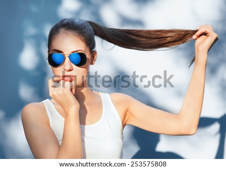 Portrait of beautiful brunette girl in mirrored blue sunglasses