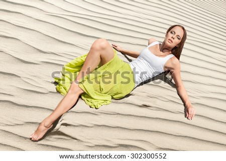 Beautiful young woman lying in sandy dunes. Fashion style concept