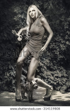 Black and white picture of young seductive woman posing with toy dog at city park
