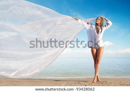Beautiful girl holding white cloth against blue sky