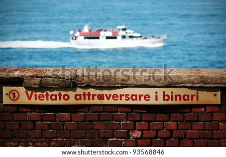 Do not cross the railway in Italian language, sea on the background