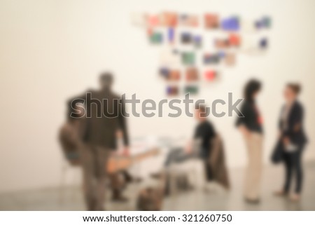 People visit an art exhibition, intentionally blurred post production.