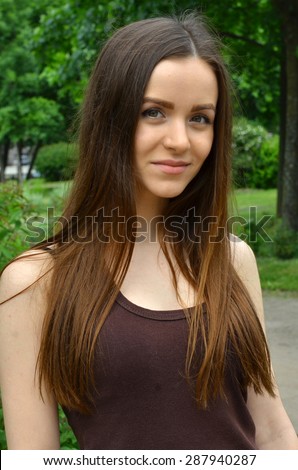 beautiful slender fair-skinned girl smiling. It stands on a green background, in nature. Fresh air. Summer.