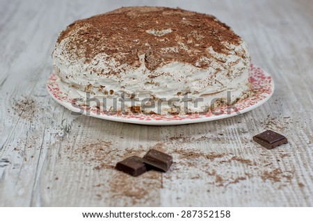 sweet brownie chocolate cream cake topped with black chocolate and cream with chocolate on wooden background