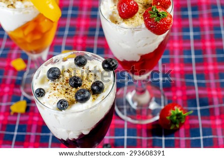 Closeup of homemade fruit jelly with strawberries, blueberries and peaches in glasses on table