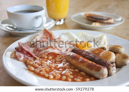 cooked breakfast on a wooden table with coffee and orange juice