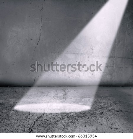 A spotlight shines into what could be a prison cell or generally an old grunge textured room and walls.