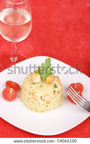 Risotto with shrimps elegantly served on a white plate. Studio shot over red background. Shallow DOF