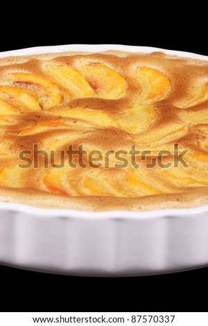 Peach tart in a white pottery cake tin. Isolated on black