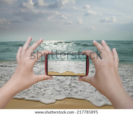 Hands taking photo beach with smartphone