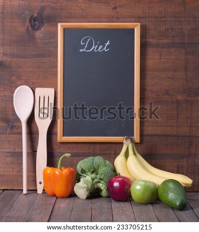 Black chalkboard for menu and fresh vegetables over wooden background. Diet food  concept.